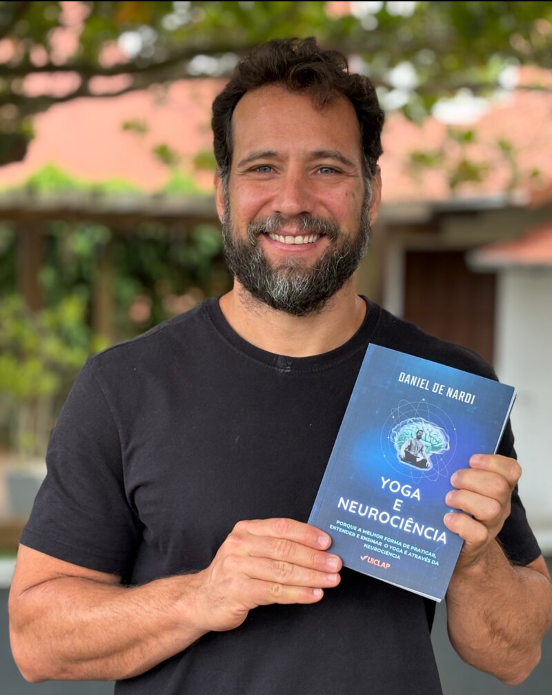 Daniel De Nardi segurando o livro impresso Yoga com Neurociência